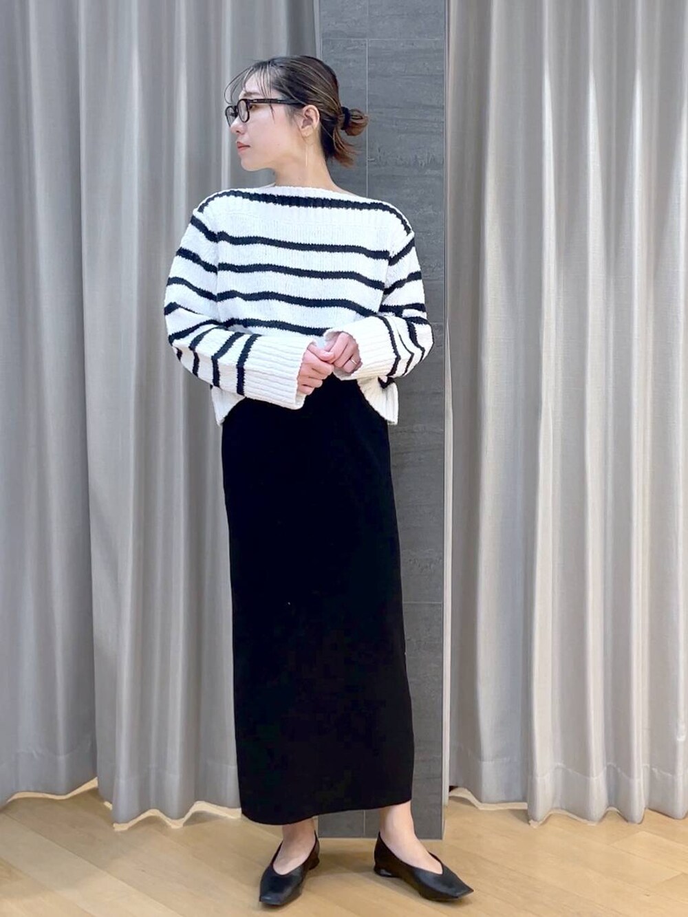 ブラック系のパンプス、ブラック系のスカート、ホワイト系のニット/セーターを着用したレディースの冬コーディネートの2枚目の写真