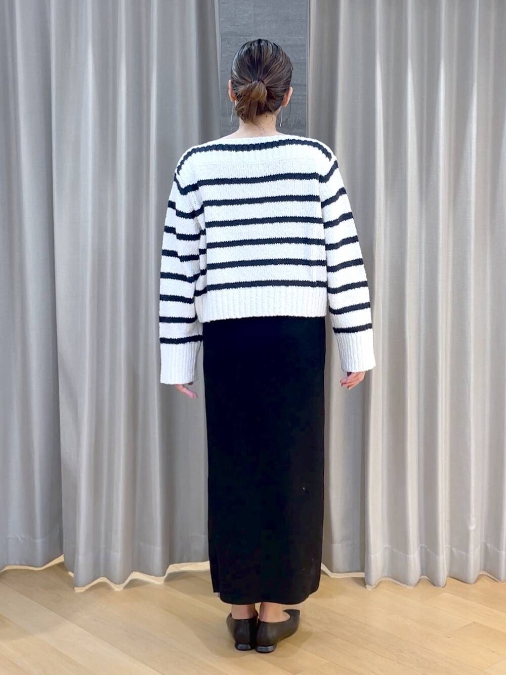 ブラック系のパンプス、ブラック系のスカート、ホワイト系のニット/セーターを着用したレディースの冬コーディネートの4枚目の写真