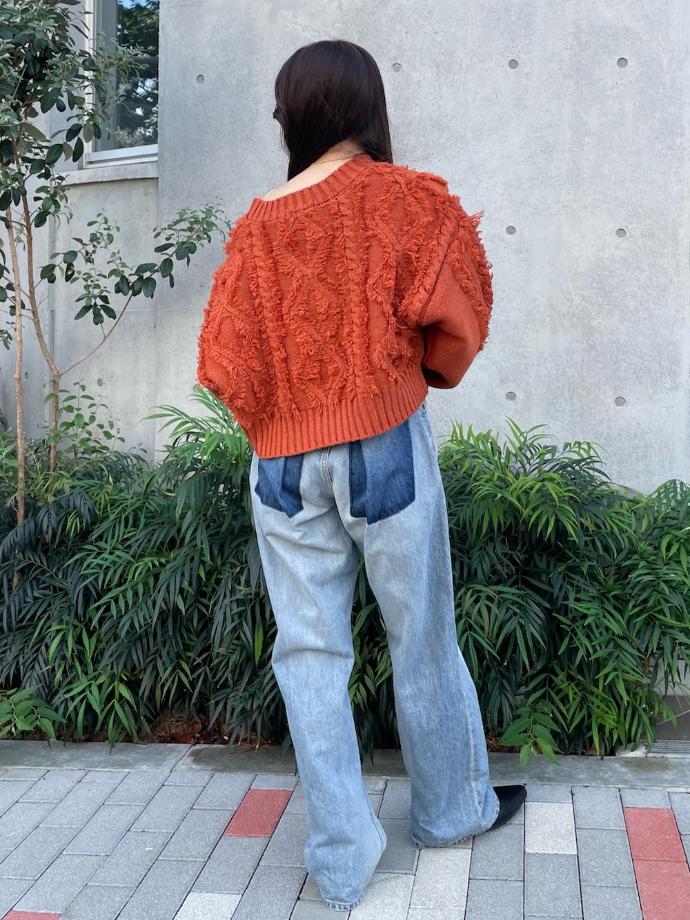 ブルー系のデニムパンツ、ブラック系のブーツ、オレンジ系のニット/セーターを着用したレディースの秋コーディネートの3枚目の写真