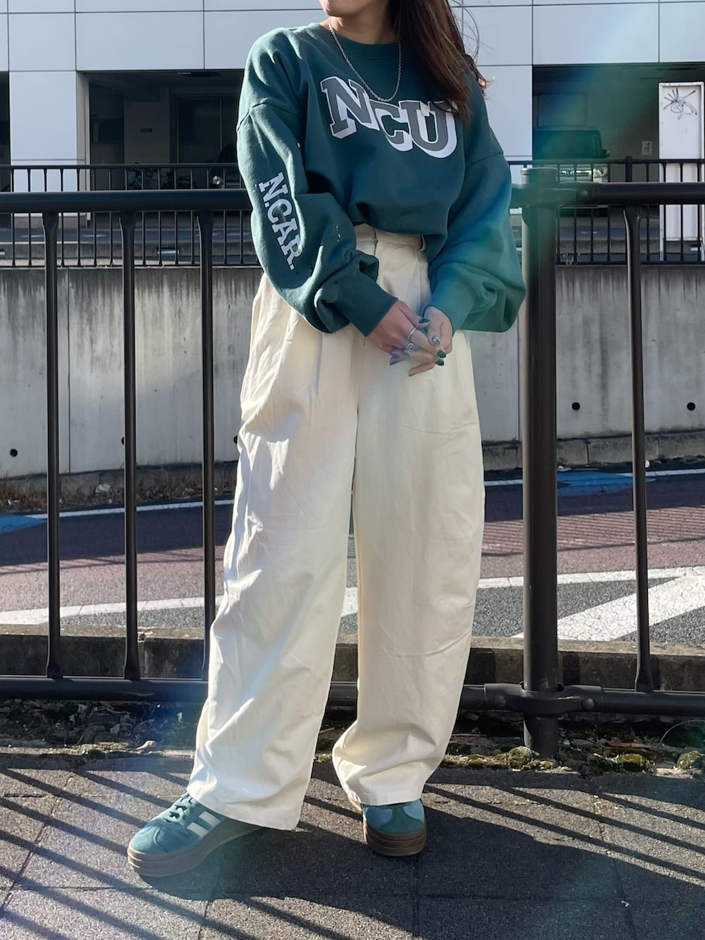 グリーン系のスウェット、ホワイト系のチノパンツを着用したレディースの冬コーディネートの2枚目の写真