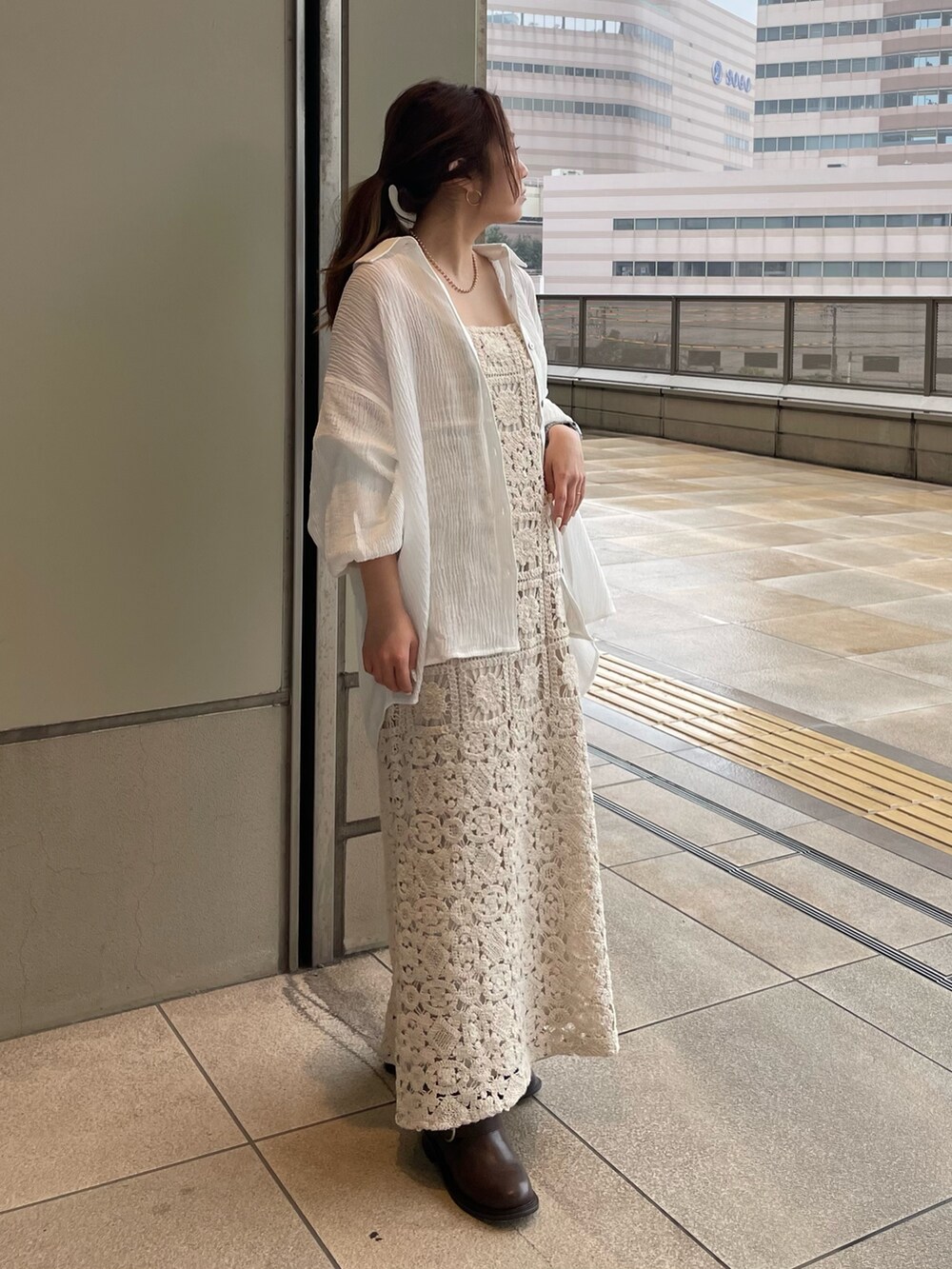 ベージュ系のワンピース、ホワイト系のシャツ/ブラウス、ブラウン系のブーツを着用したレディースの春コーディネートの2枚目の写真