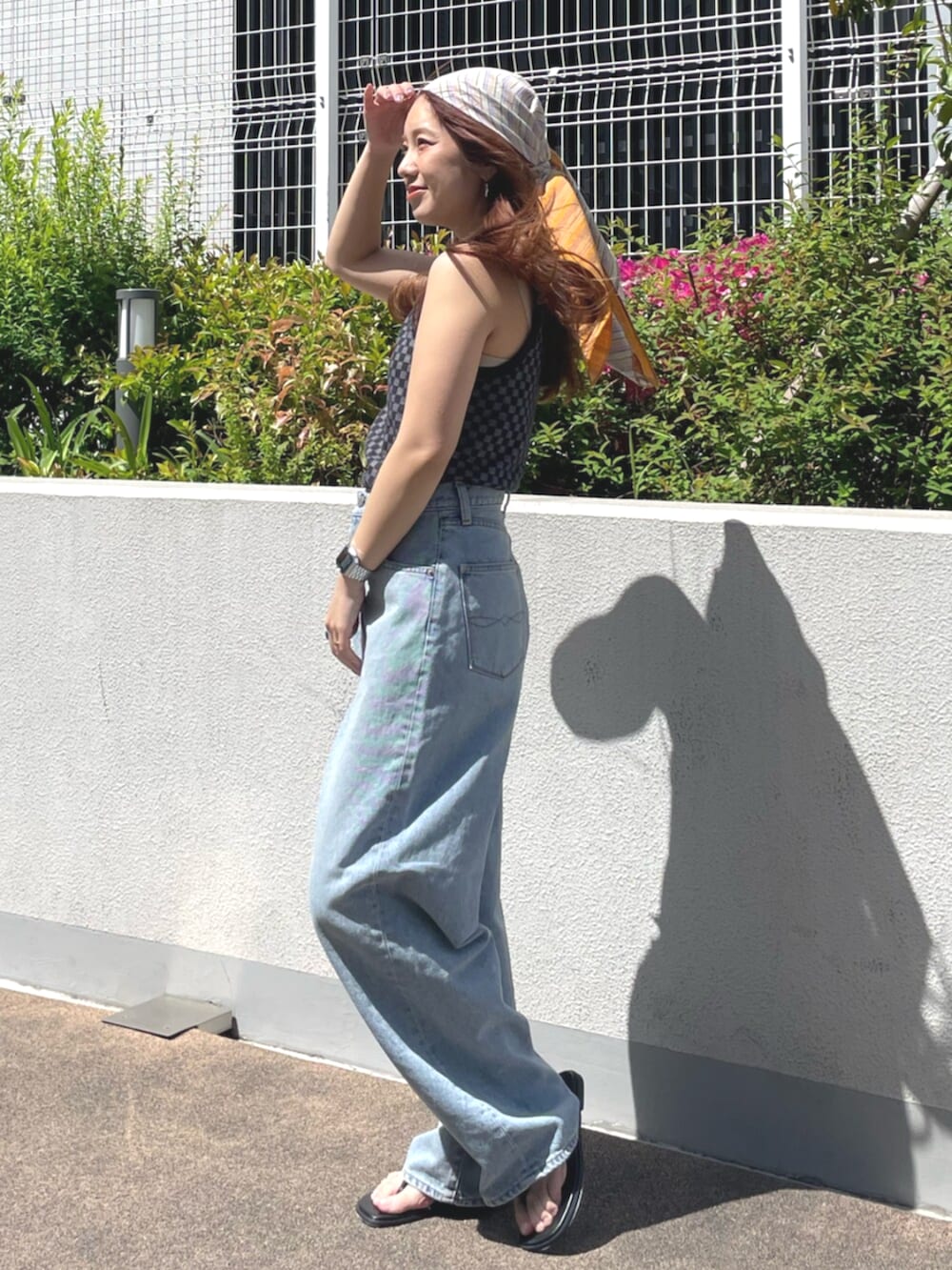 ブラック系のタンクトップ、ブルー系のデニムパンツ、ブラック系のサンダルを着用したレディースの春コーディネートの2枚目の写真