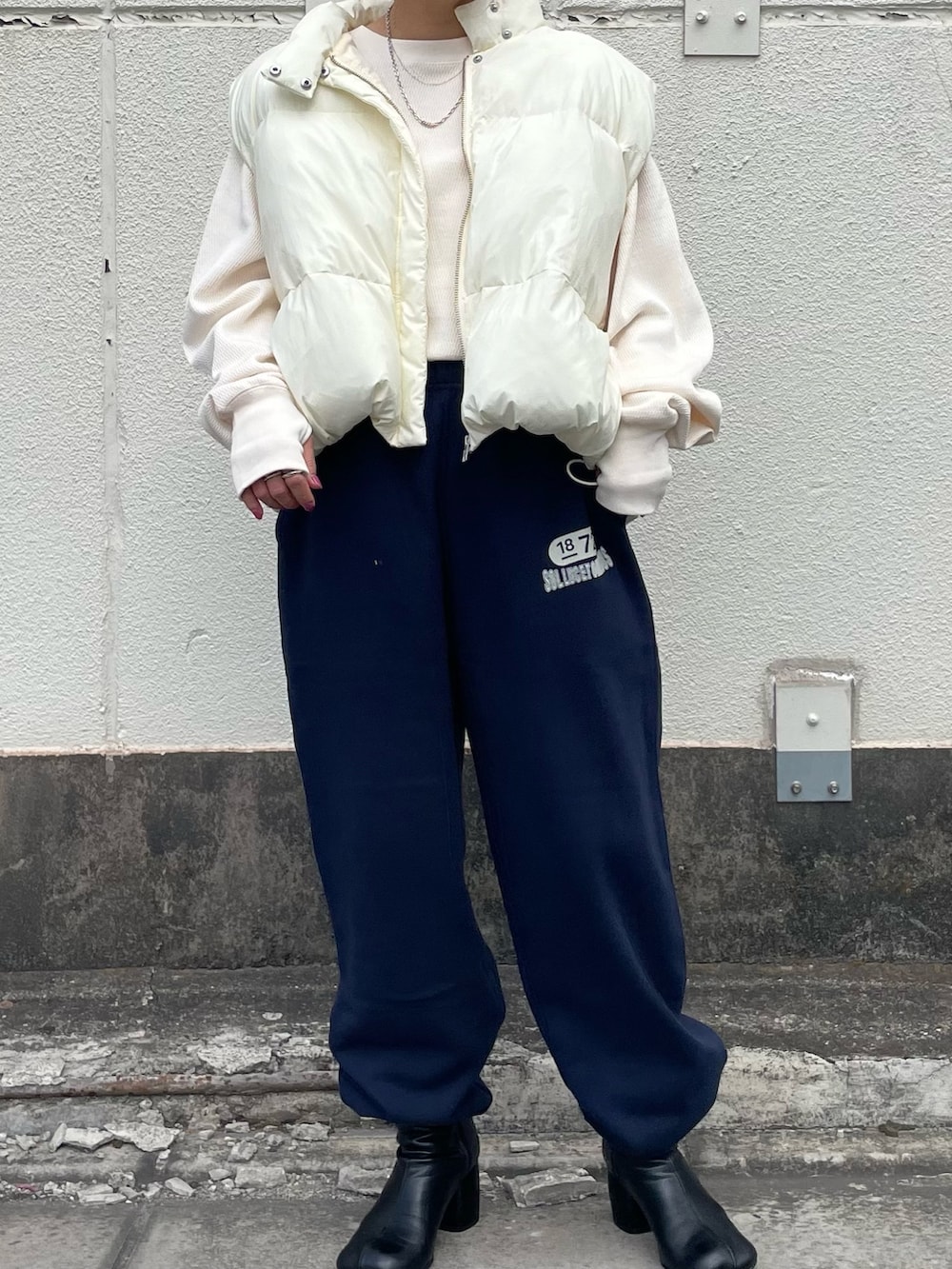ホワイト系のダウンベスト、ホワイト系のTシャツ/カットソー、ブルー系のスウェットパンツを着用したレディースの秋コーディネートの2枚目の写真