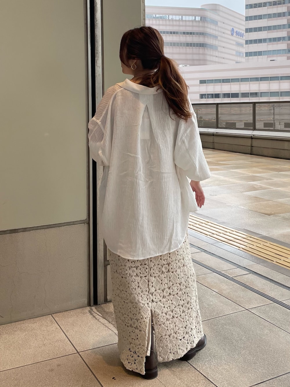 ベージュ系のワンピース、ホワイト系のシャツ/ブラウス、ブラウン系のブーツを着用したレディースの春コーディネートの3枚目の写真