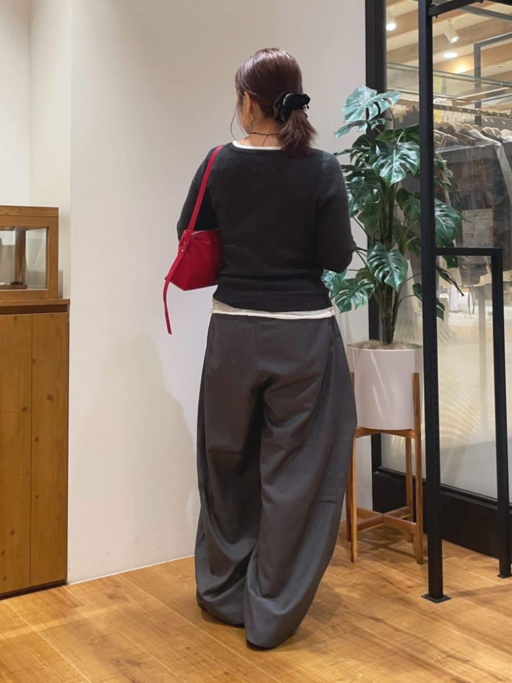 グレー系のニット/セーター、グレー系のその他パンツ、レッド系のハンドバッグを着用したレディースの秋コーディネートの3枚目の写真