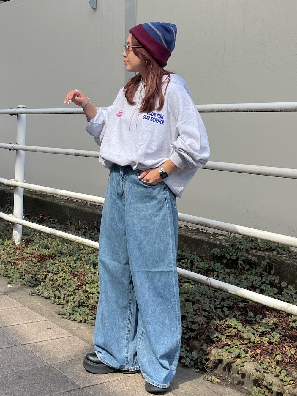 ホワイト系のパーカー、ブルー系のデニムパンツ、レッド系のニットキャップ/ビーニーを着用したレディースの秋コーディネートの4枚目の写真