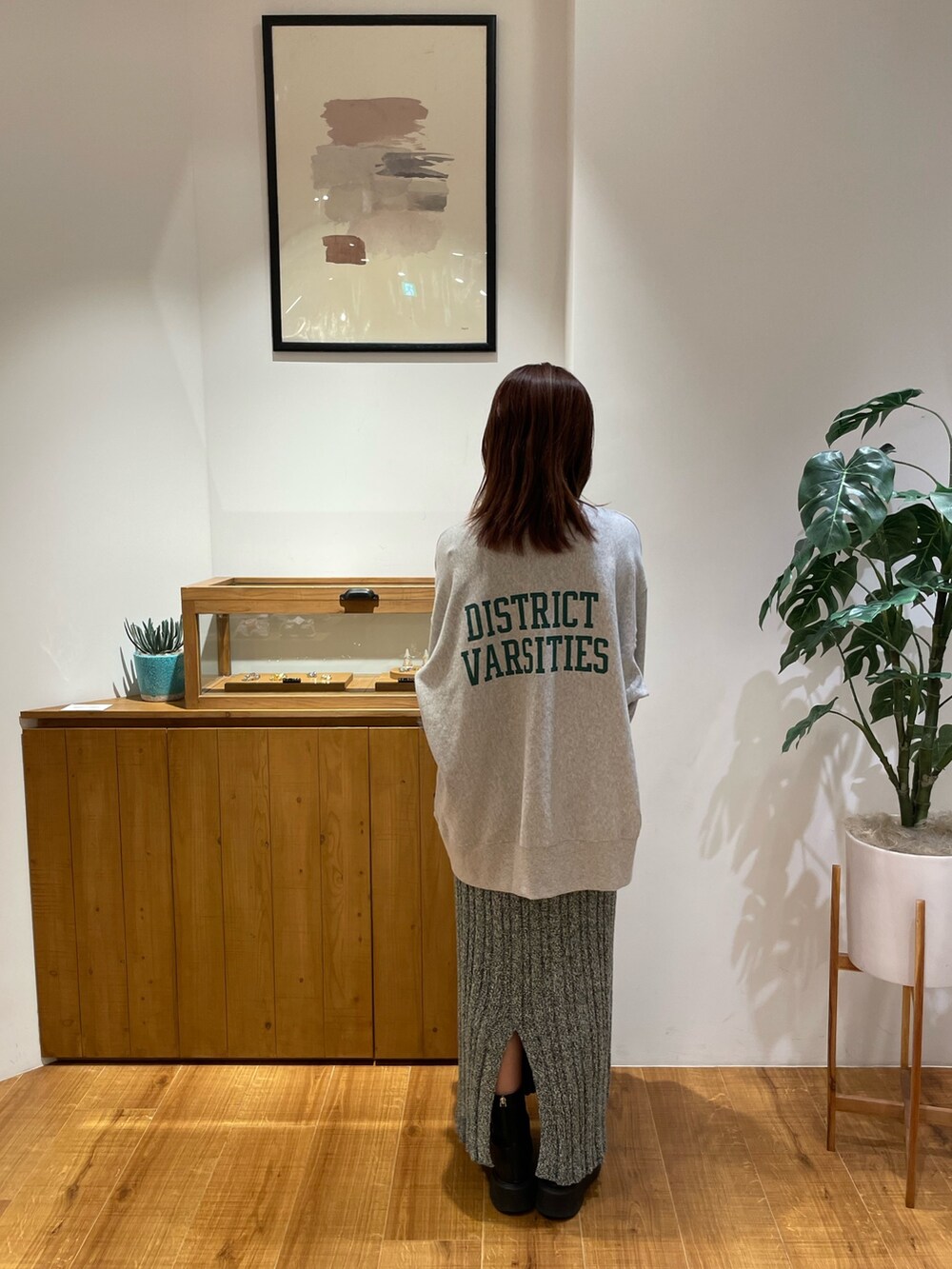 グレー系のスウェット、グレー系のハンドバッグ、グリーン系のスカートを着用したレディースの秋コーディネートの2枚目の写真