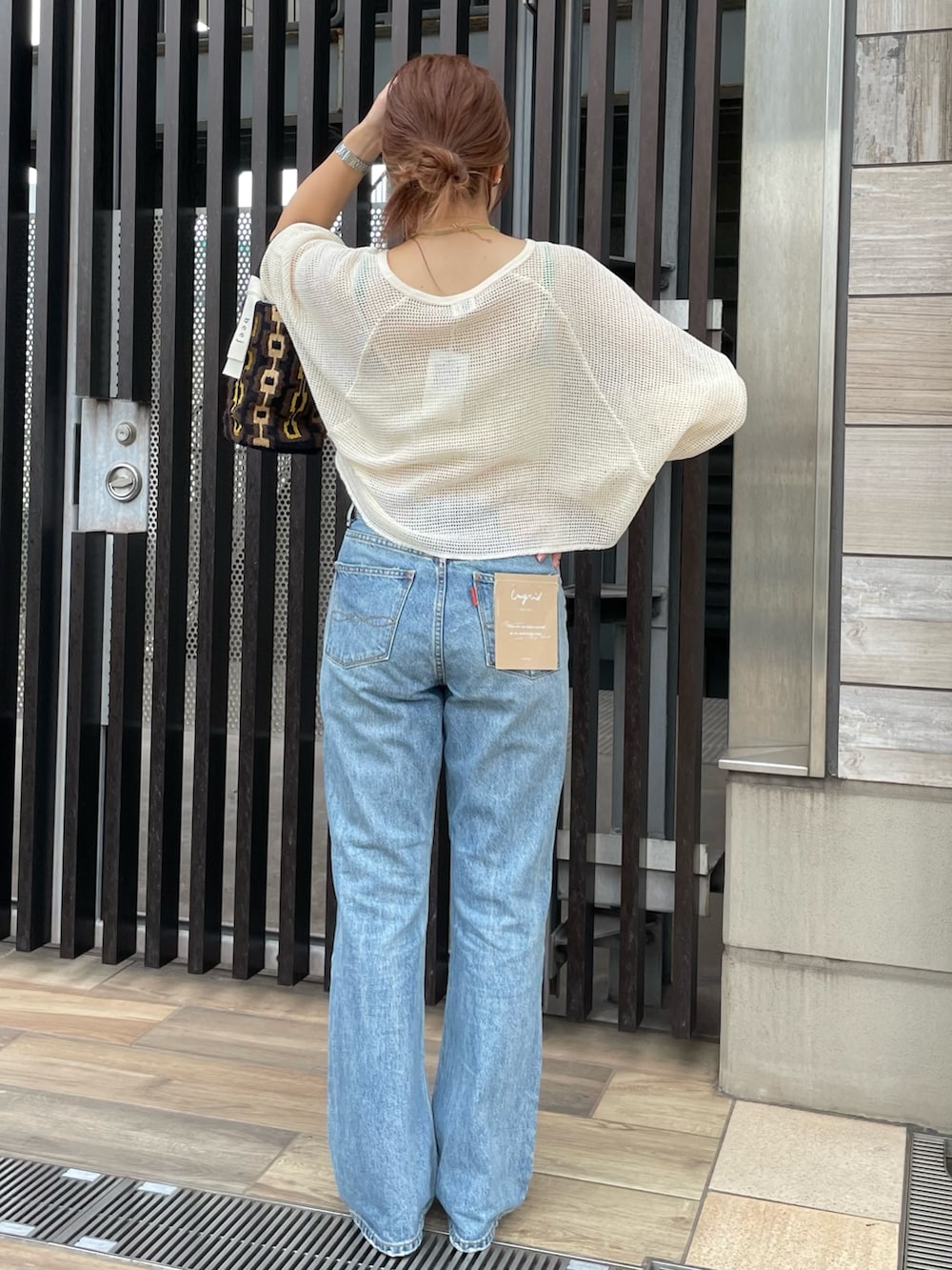 ブルー系のデニムパンツ、ホワイト系のTシャツ/カットソー、ブラウン系のハンドバッグを着用したレディースの夏コーディネートの3枚目の写真