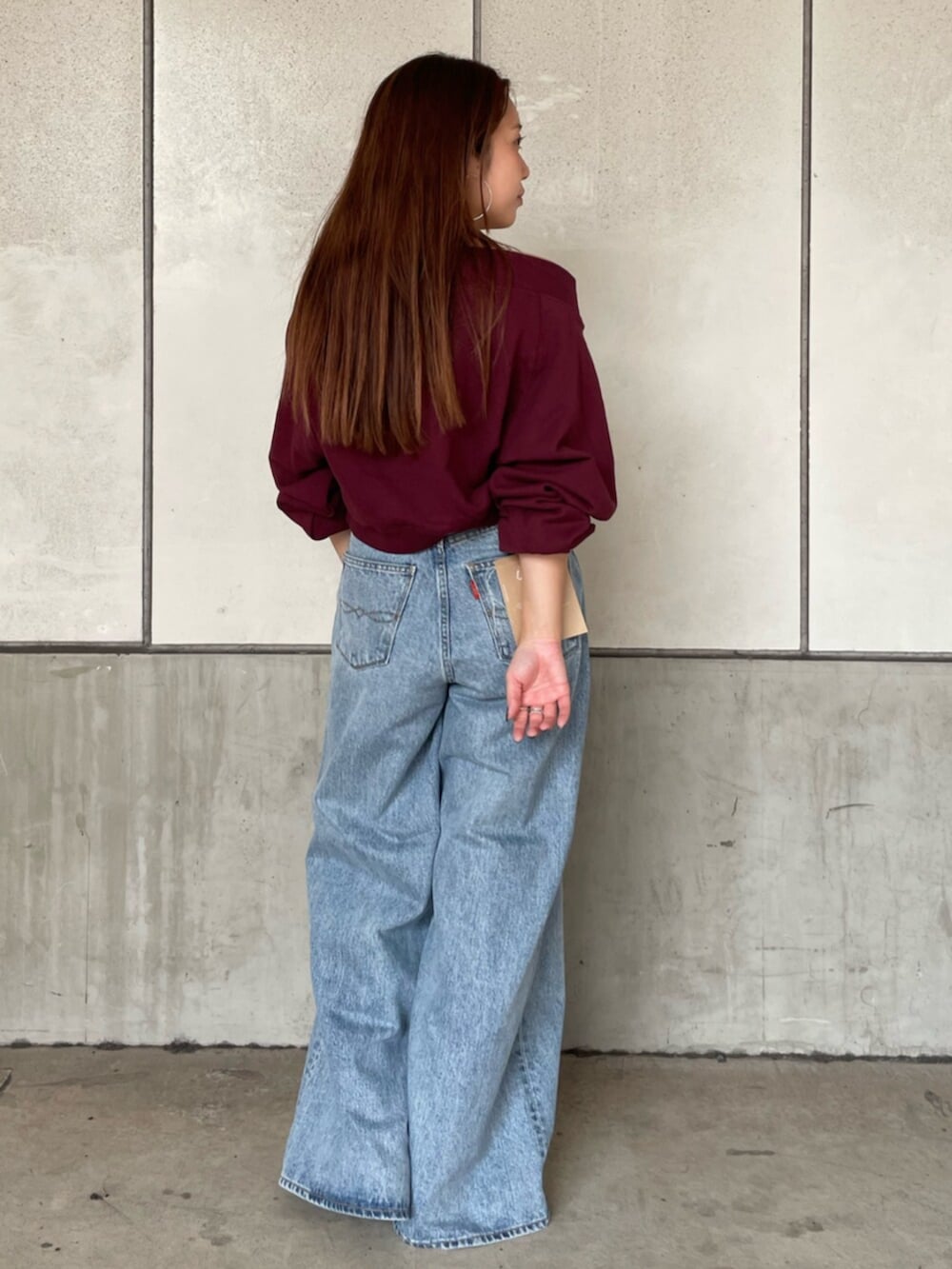 レッド系のスウェット、ブルー系のデニムパンツを着用したレディースの秋コーディネートの3枚目の写真