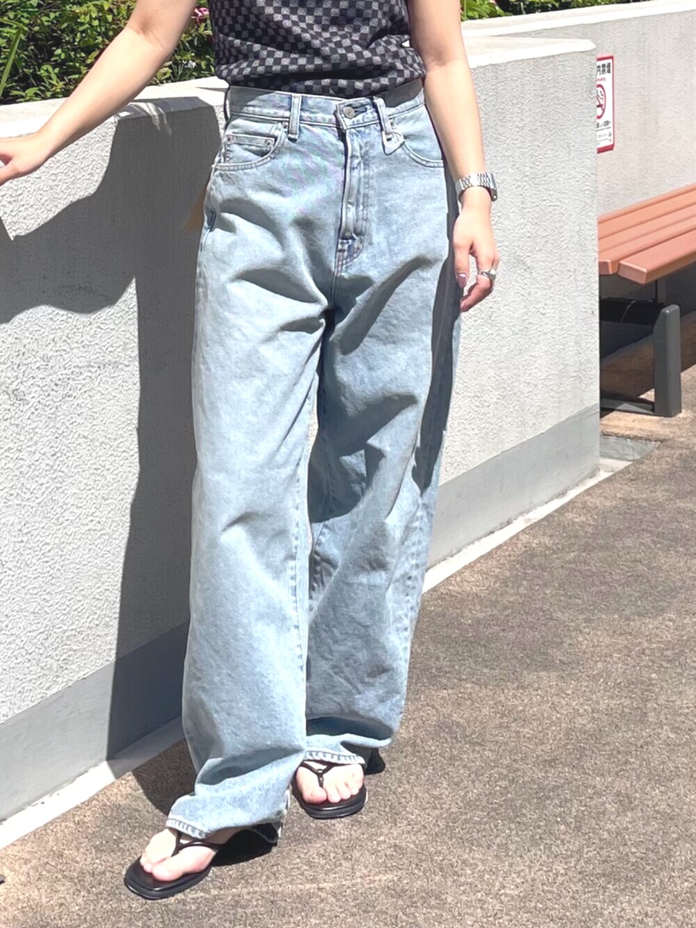 ブラック系のタンクトップ、ブルー系のデニムパンツ、ブラック系のサンダルを着用したレディースの春コーディネートの4枚目の写真