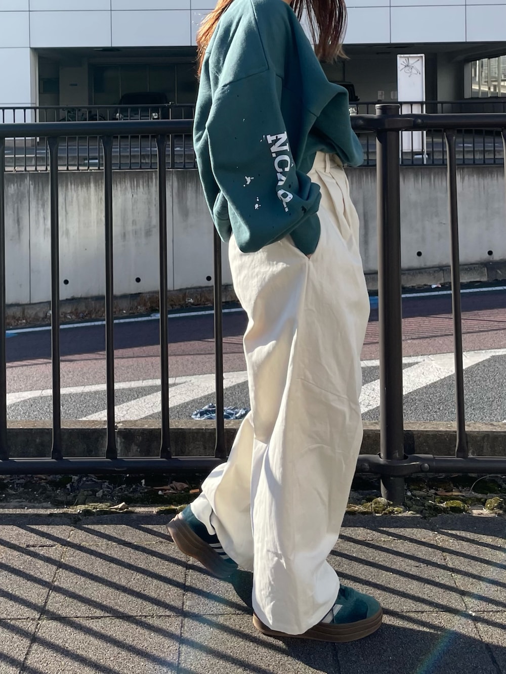 グリーン系のスウェット、ホワイト系のチノパンツを着用したレディースの冬コーディネートの3枚目の写真