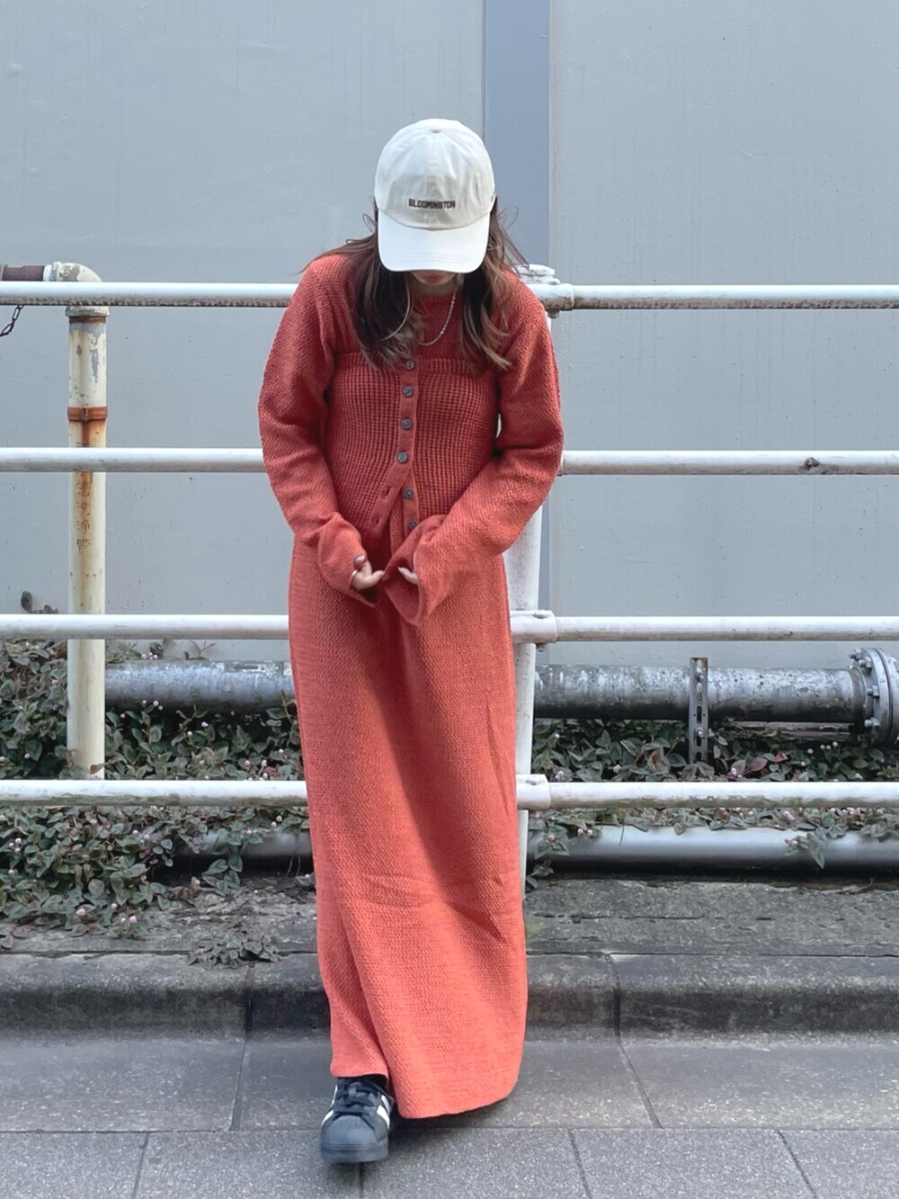 オレンジ系のワンピース、ホワイト系のキャップを着用したレディースの冬コーディネートの5枚目の写真