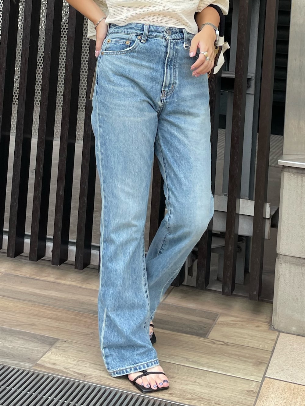 ブルー系のデニムパンツ、ホワイト系のTシャツ/カットソー、ブラウン系のハンドバッグを着用したレディースの夏コーディネートの4枚目の写真