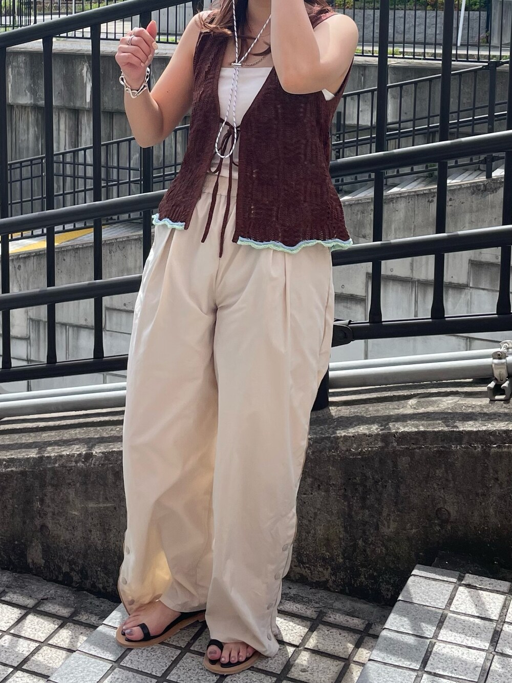 ブラウン系のニット/セーター、ホワイト系のその他パンツ、ブラック系のサンダルを着用したレディースの春コーディネートの5枚目の写真