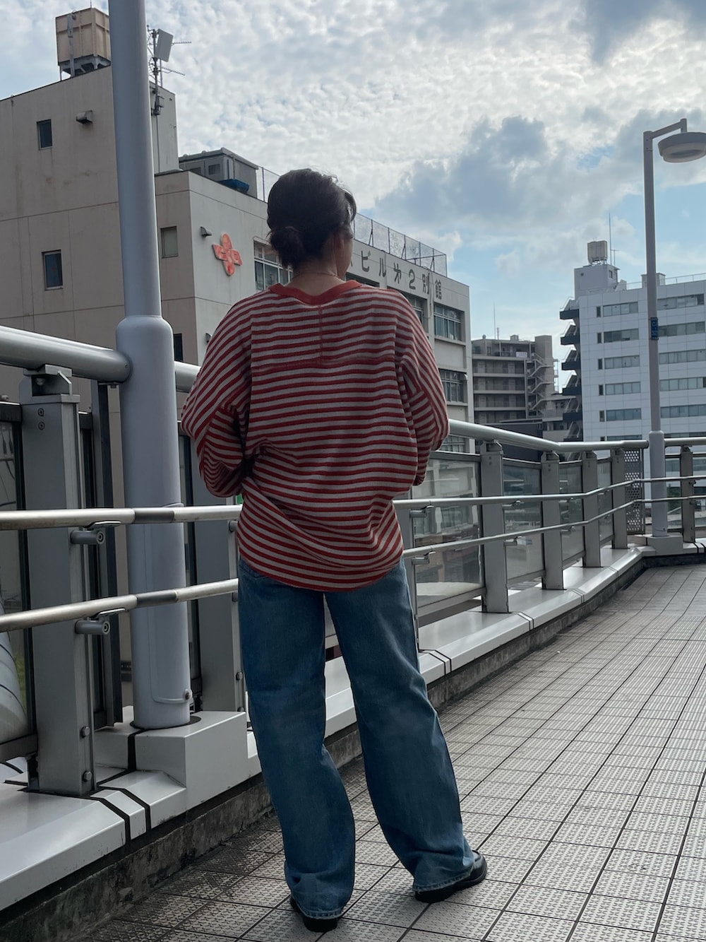 オレンジ系のTシャツ/カットソー、ブラック系のローファー、ブルー系のデニムパンツを着用したレディースの夏コーディネートの3枚目の写真