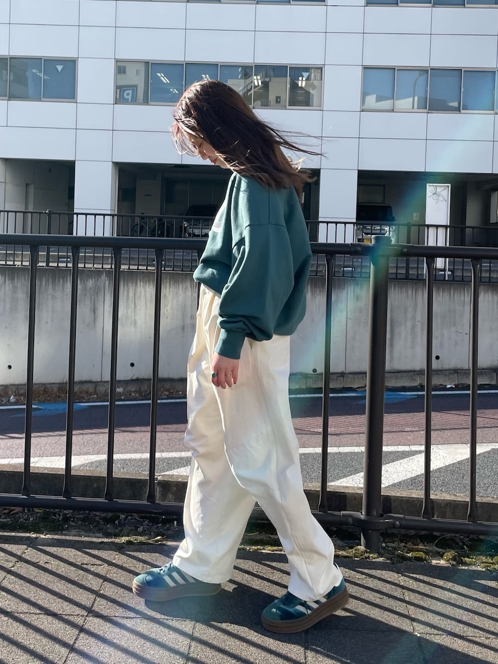 グリーン系のスウェット、ホワイト系のチノパンツを着用したレディースの冬コーディネートの4枚目の写真