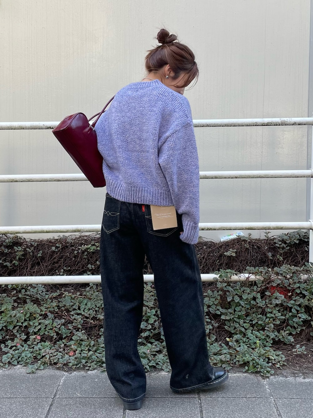 ブラック系のデニムパンツ、パープル系のニット/セーター、レッド系のハンドバッグを着用したレディースの秋コーディネートの3枚目の写真