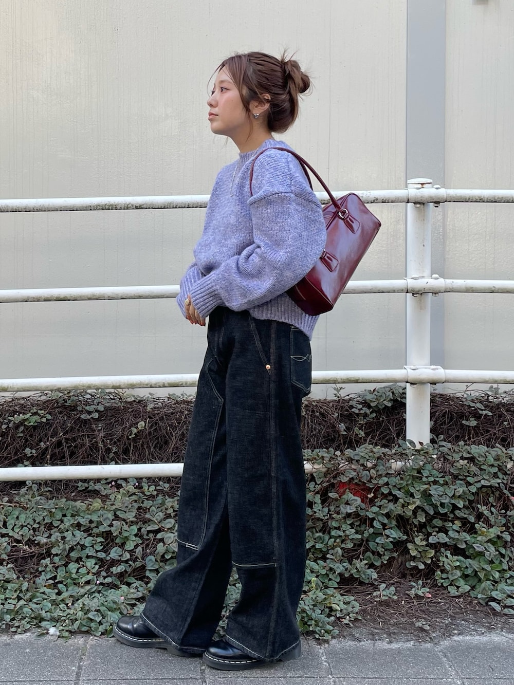 ブラック系のデニムパンツ、パープル系のニット/セーター、レッド系のハンドバッグを着用したレディースの秋コーディネートの2枚目の写真