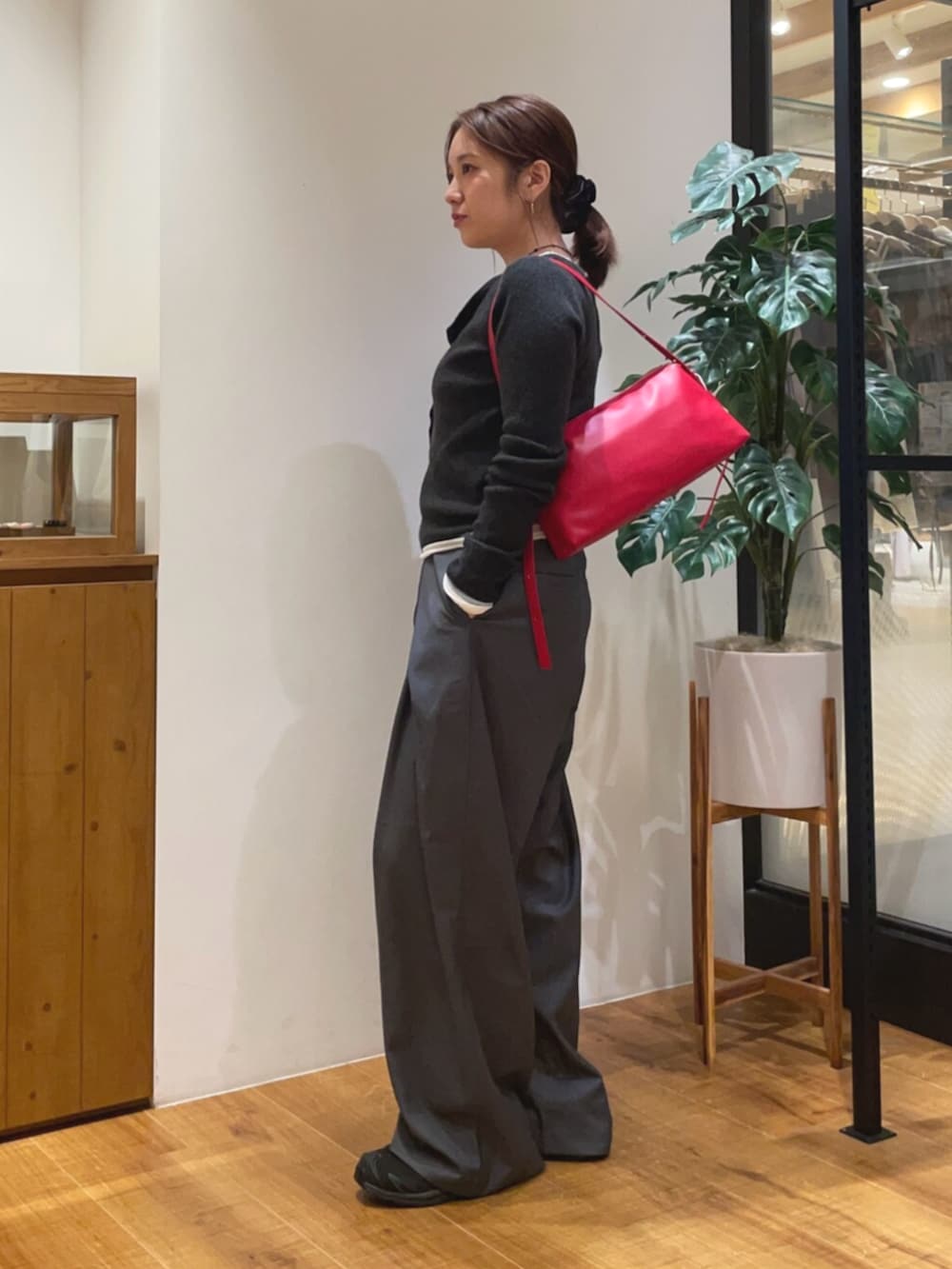 グレー系のニット/セーター、グレー系のその他パンツ、レッド系のハンドバッグを着用したレディースの秋コーディネートの2枚目の写真