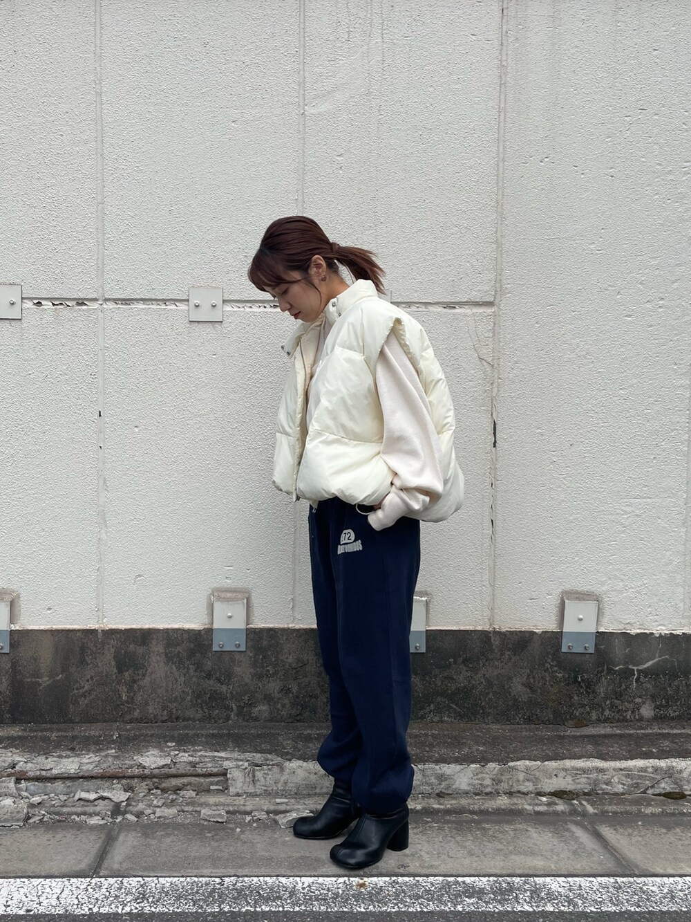 ホワイト系のダウンベスト、ホワイト系のTシャツ/カットソー、ブルー系のスウェットパンツを着用したレディースの秋コーディネートの3枚目の写真