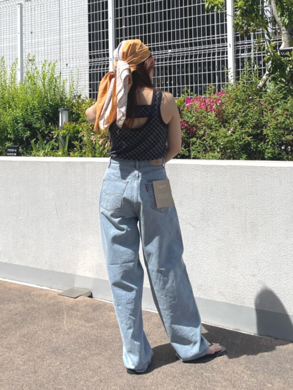 ブラック系のタンクトップ、ブルー系のデニムパンツ、ブラック系のサンダルを着用したレディースの春コーディネートの3枚目の写真