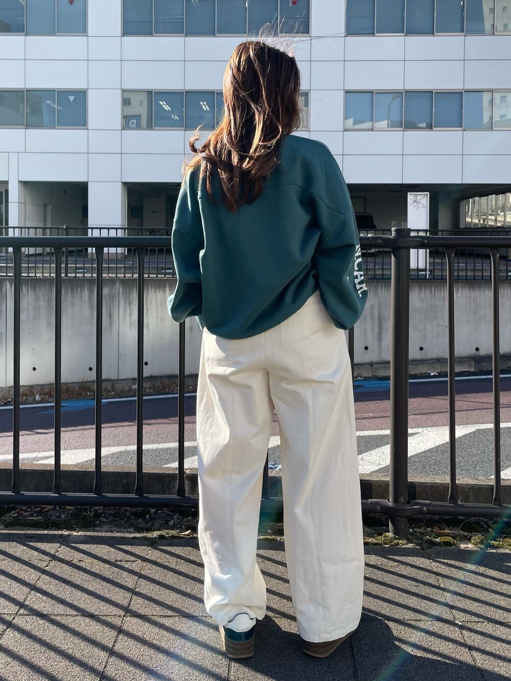 グリーン系のスウェット、ホワイト系のチノパンツを着用したレディースの冬コーディネートの5枚目の写真