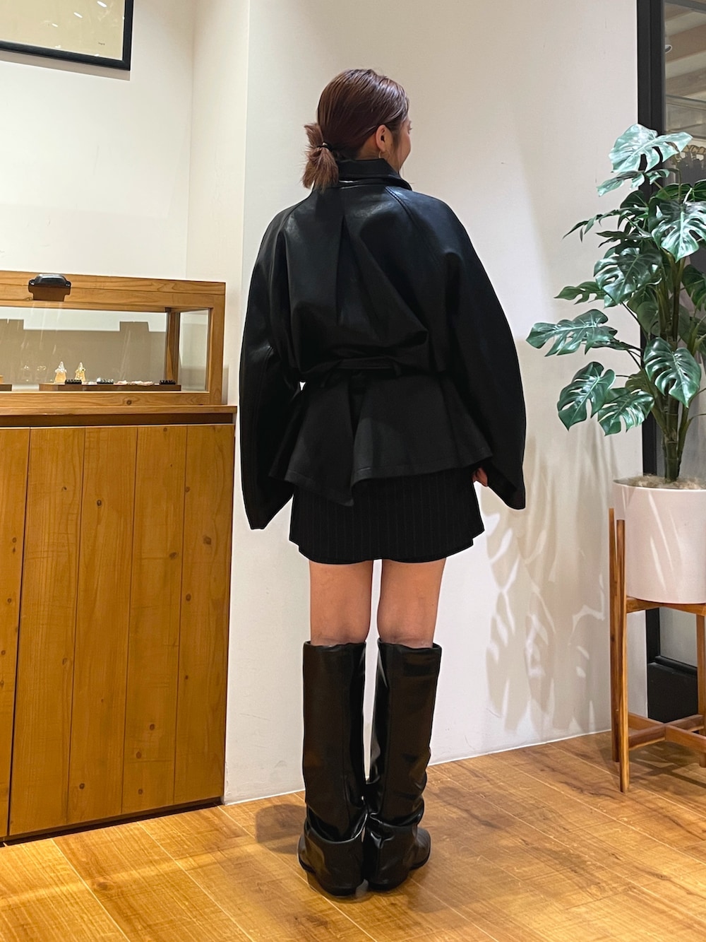 ブラック系のトレンチコート、ブルー系のスカート、ブラック系のブーツを着用したレディースの秋コーディネートの3枚目の写真