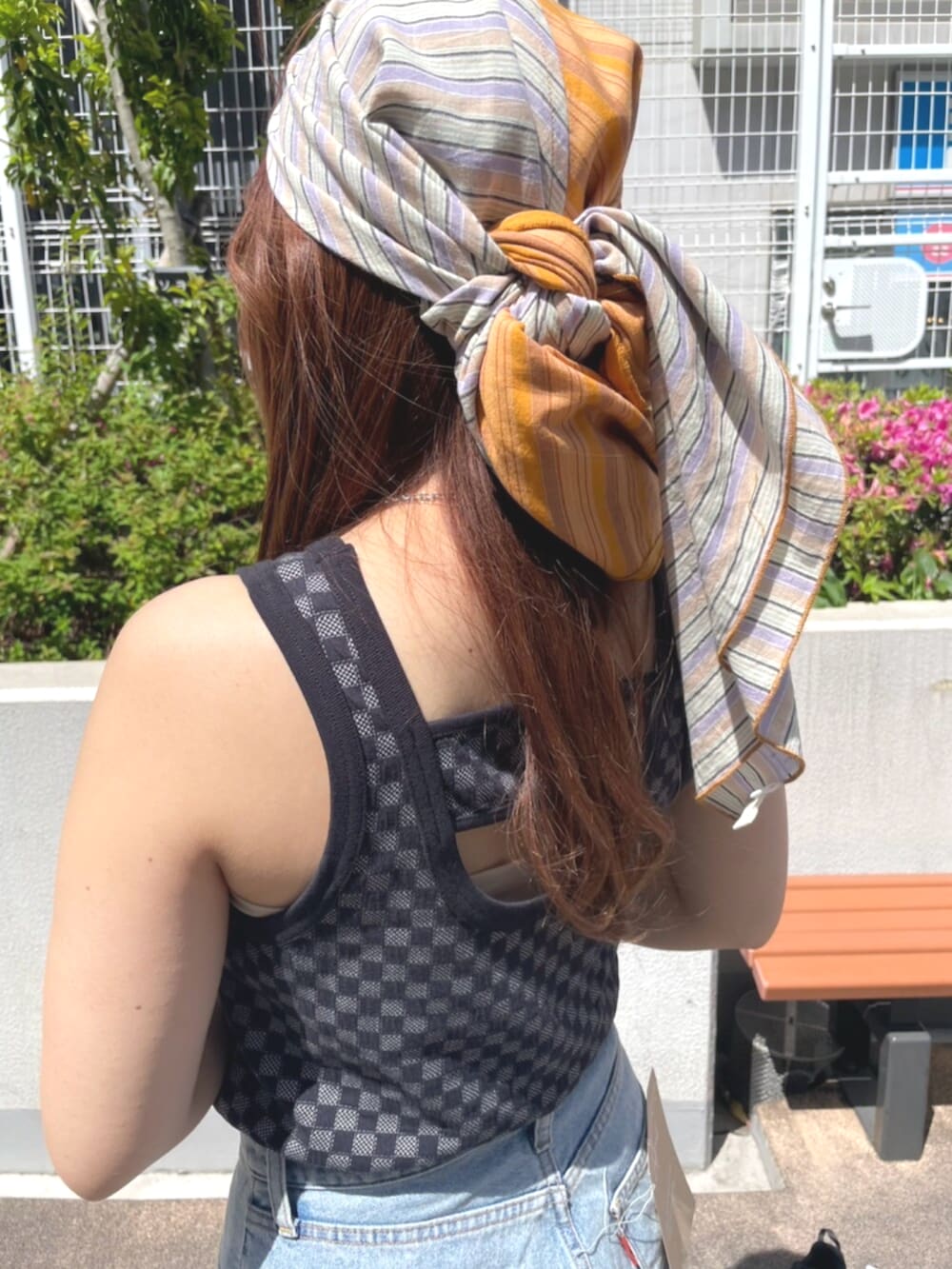 ブラック系のタンクトップ、ブルー系のデニムパンツ、ブラック系のサンダルを着用したレディースの春コーディネートの5枚目の写真