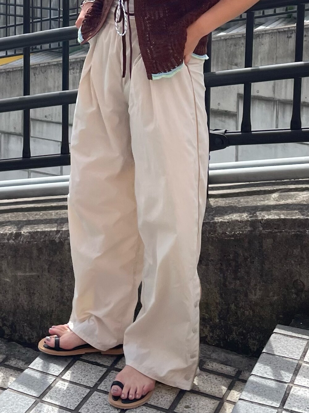 ブラウン系のニット/セーター、ホワイト系のその他パンツ、ブラック系のサンダルを着用したレディースの春コーディネートの4枚目の写真