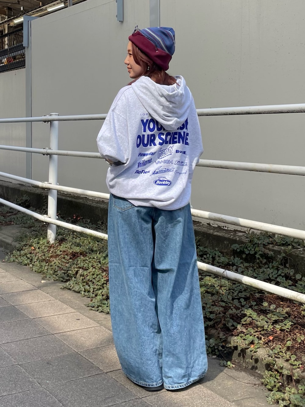 ホワイト系のパーカー、ブルー系のデニムパンツ、レッド系のニットキャップ/ビーニーを着用したレディースの秋コーディネートの3枚目の写真