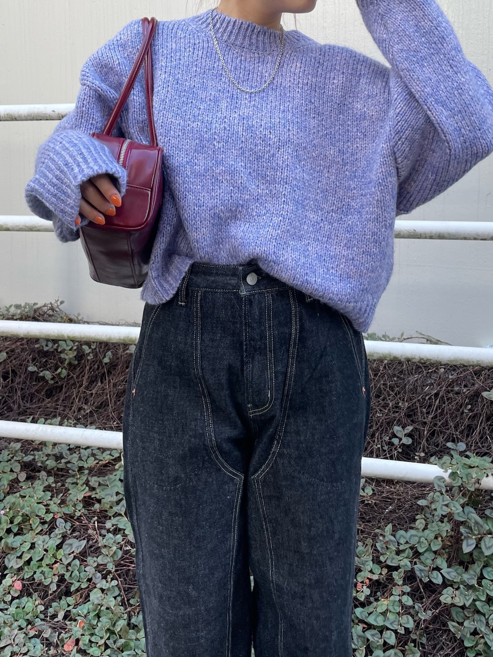 ブラック系のデニムパンツ、パープル系のニット/セーター、レッド系のハンドバッグを着用したレディースの秋コーディネートの4枚目の写真