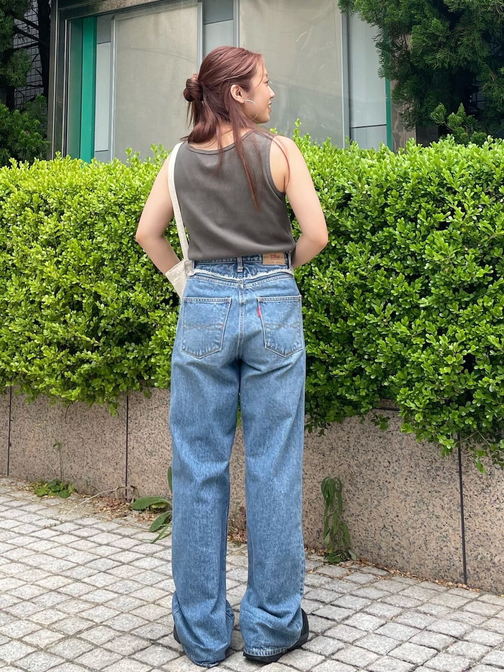 グレー系のタンクトップ、ブルー系のデニムパンツを着用したレディースの夏コーディネートの3枚目の写真
