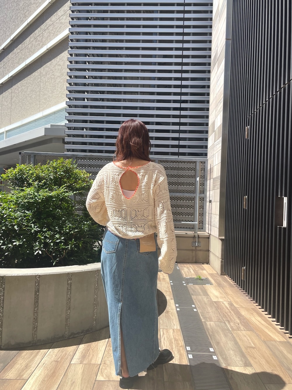 ホワイト系のニット/セーター、ブルー系のデニムスカートを着用したレディースの夏コーディネートの2枚目の写真