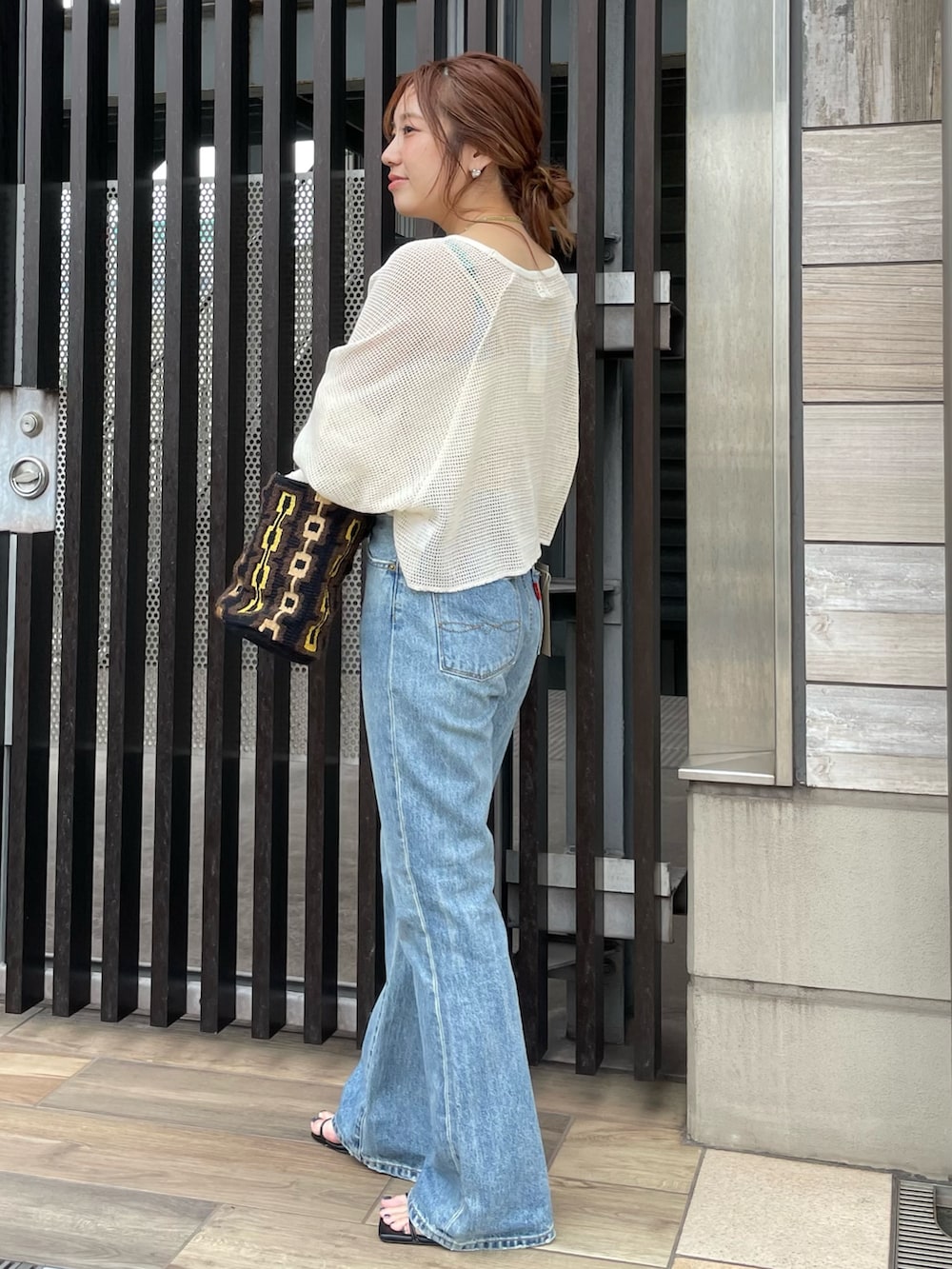 ブルー系のデニムパンツ、ホワイト系のTシャツ/カットソー、ブラウン系のハンドバッグを着用したレディースの夏コーディネートの2枚目の写真