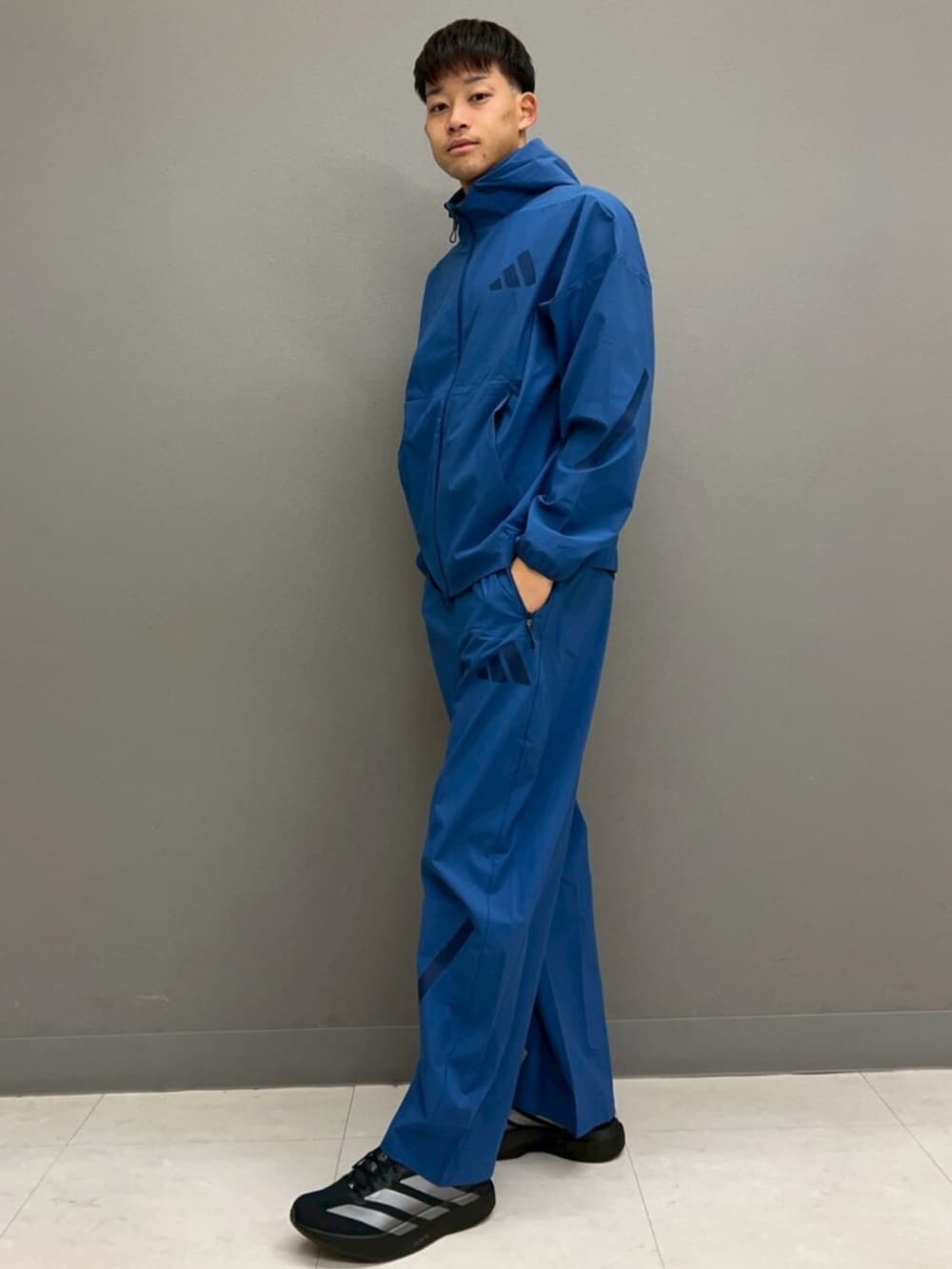 ブルー系のジャージ、ブルー系のその他パンツ、ブラック系のTシャツ/カットソーを着用したメンズの春コーディネートの2枚目の写真