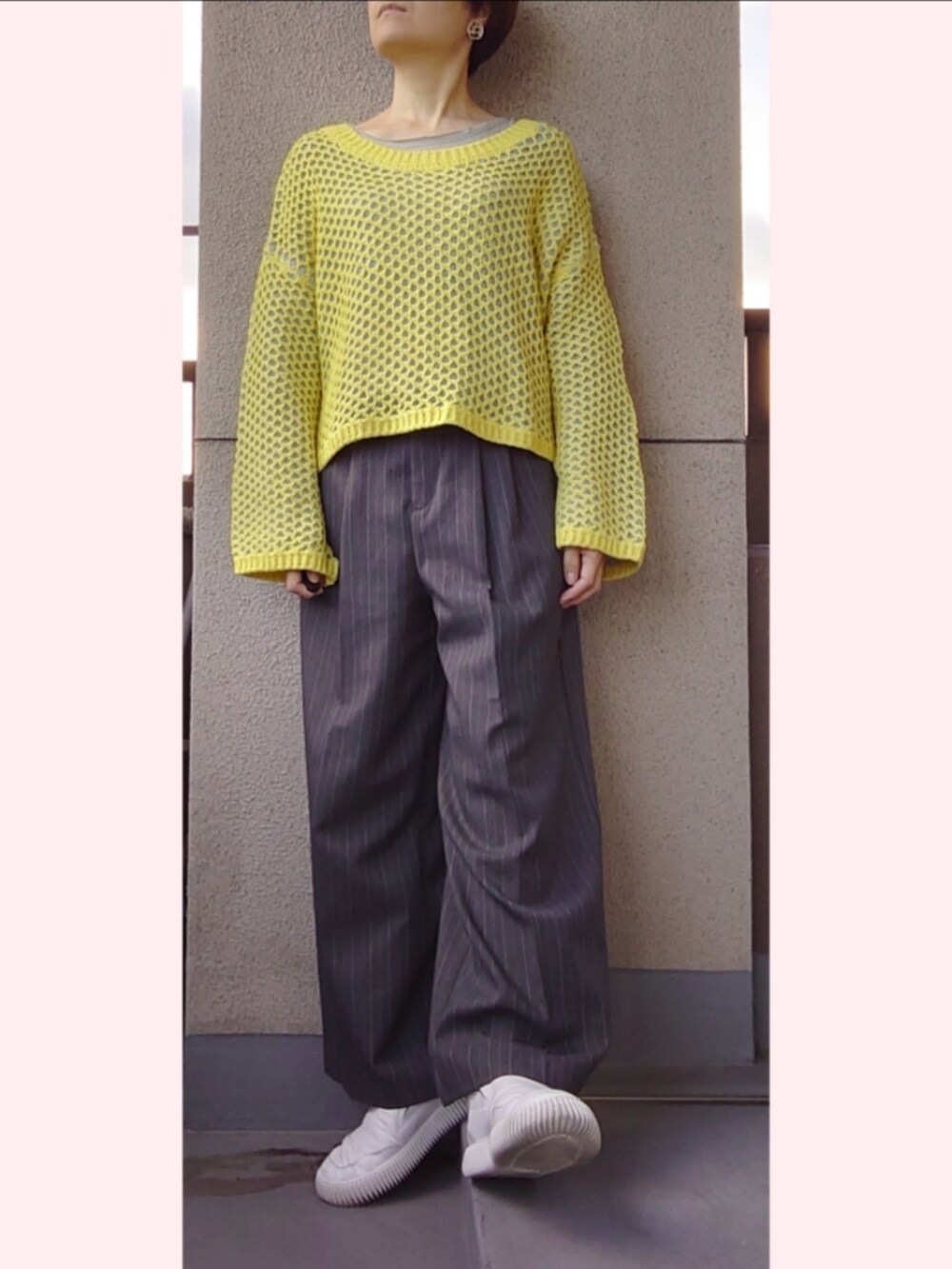 グレー系のパンツ、イエロー系のニット/セーター、ホワイト系のスニーカーを着用したレディースの秋コーディネートの2枚目の写真