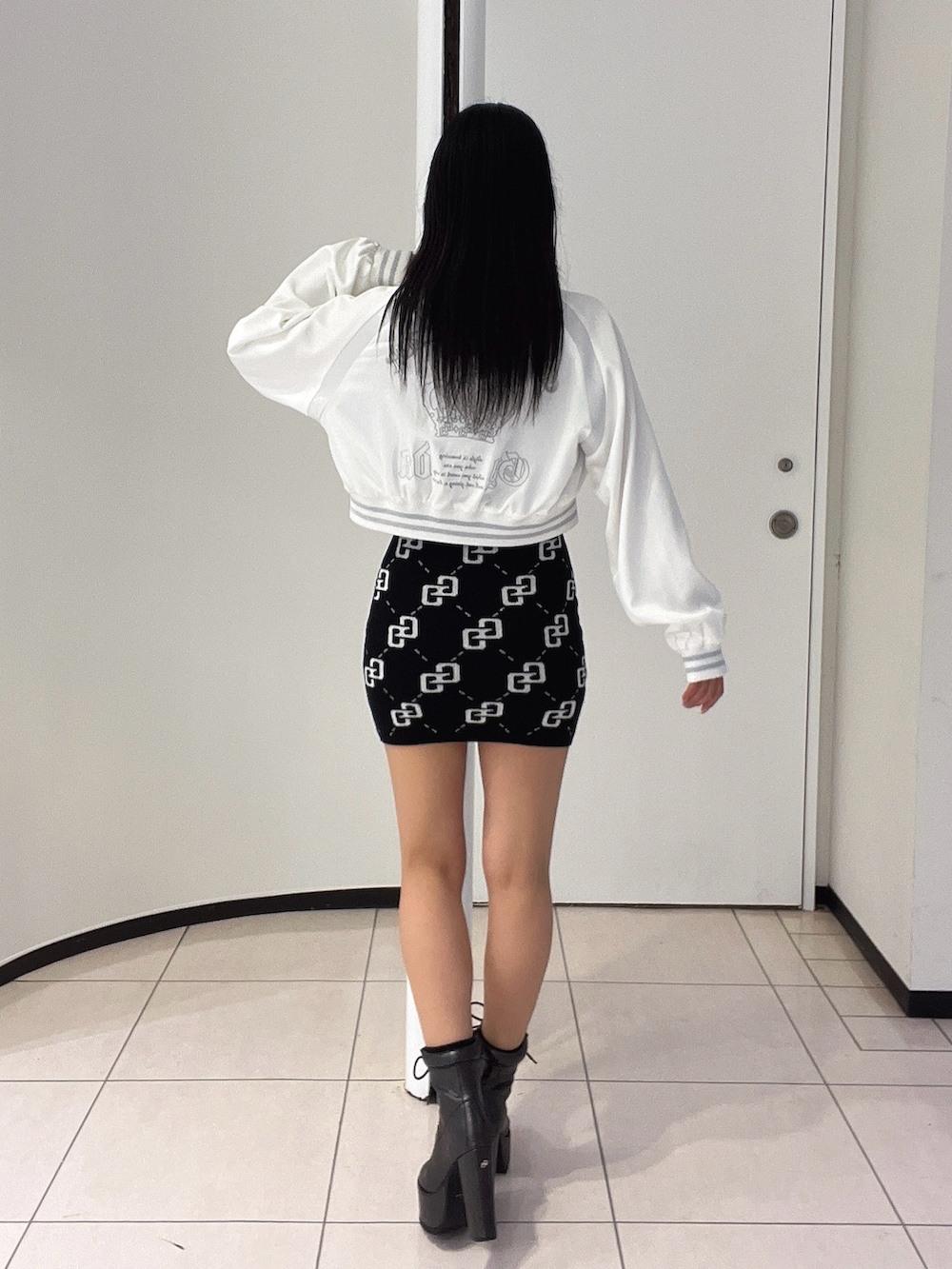 ブラック系のワンピース、ブラック系のブーツ、ホワイト系のブルゾンを着用したレディースの春コーディネートの4枚目の写真