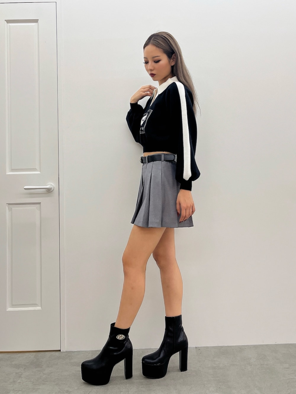 ブラック系のニット/セーター、グレー系のスカート、ブラック系のブーツを着用したレディースの冬コーディネートの2枚目の写真