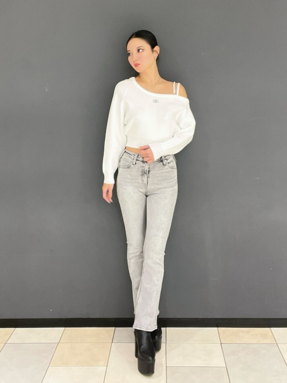 グレー系のデニムパンツ、ブラック系のブーツ、ホワイト系のニット/セーターを着用したレディースの秋コーディネートの2枚目の写真