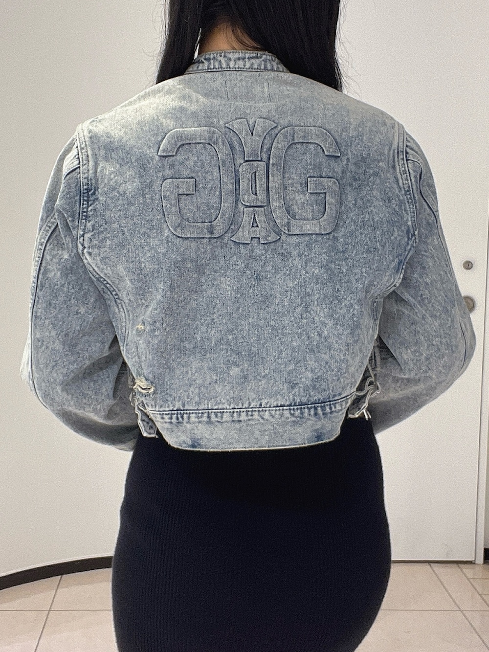 ブラック系のワンピース、ブラック系のパンプス、ブルー系のデニムジャケットを着用したレディースの春コーディネートの5枚目の写真