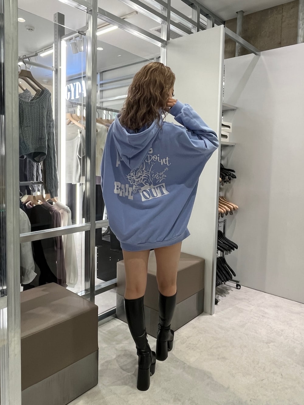 ブルー系のパーカー、シルバー系のハンドバッグ、ブラック系のブーツを着用したレディースの秋コーディネートの2枚目の写真