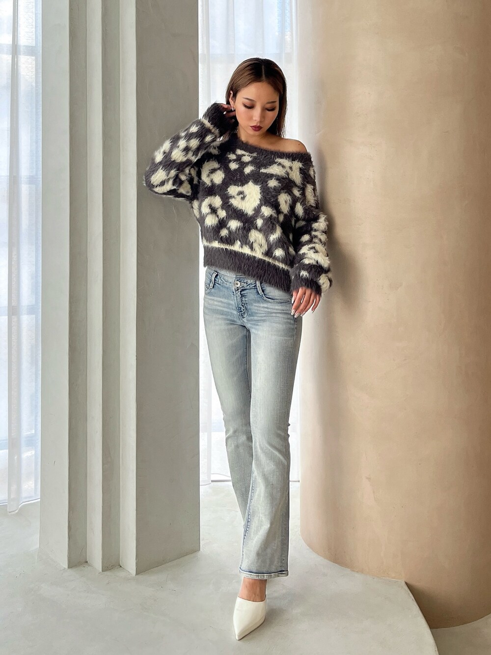 グレー系のニット/セーター、ブルー系のデニムパンツ、ホワイト系のパンプスを着用したレディースの冬コーディネートの2枚目の写真