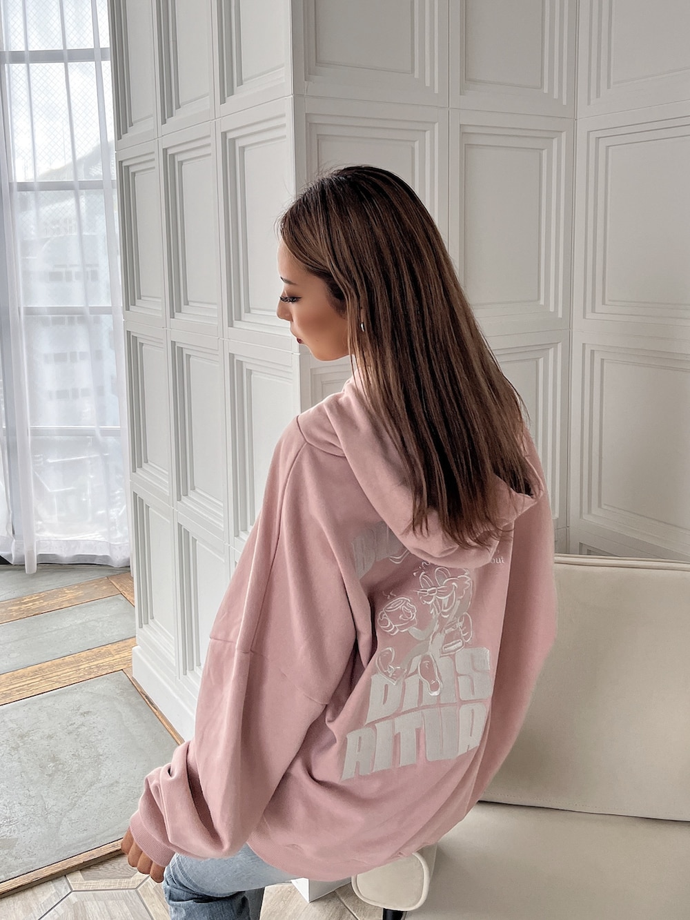 ピンク系のスウェット、ブルー系のデニムパンツ、ブラック系のブーツを着用したレディースの秋コーディネートの3枚目の写真