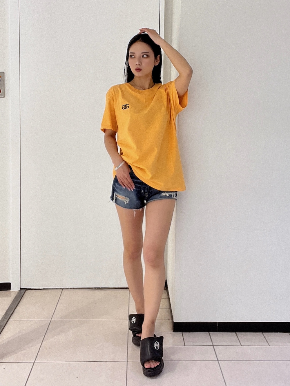 オレンジ系のTシャツ/カットソー、ブルー系のデニムパンツを着用したレディースの春コーディネートの2枚目の写真