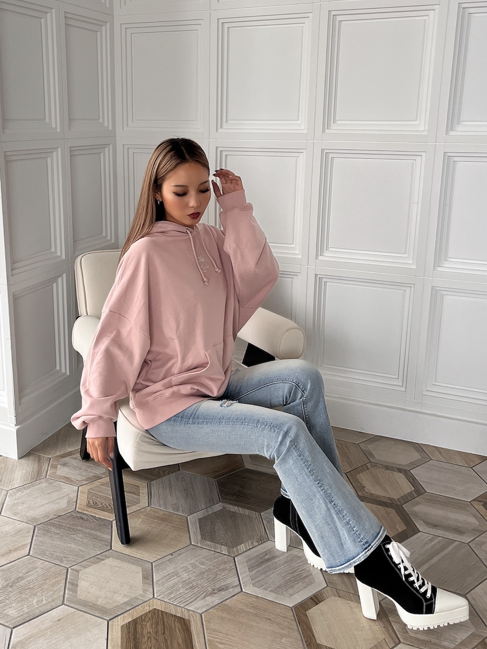 ピンク系のスウェット、ブルー系のデニムパンツ、ブラック系のブーツを着用したレディースの秋コーディネートの2枚目の写真