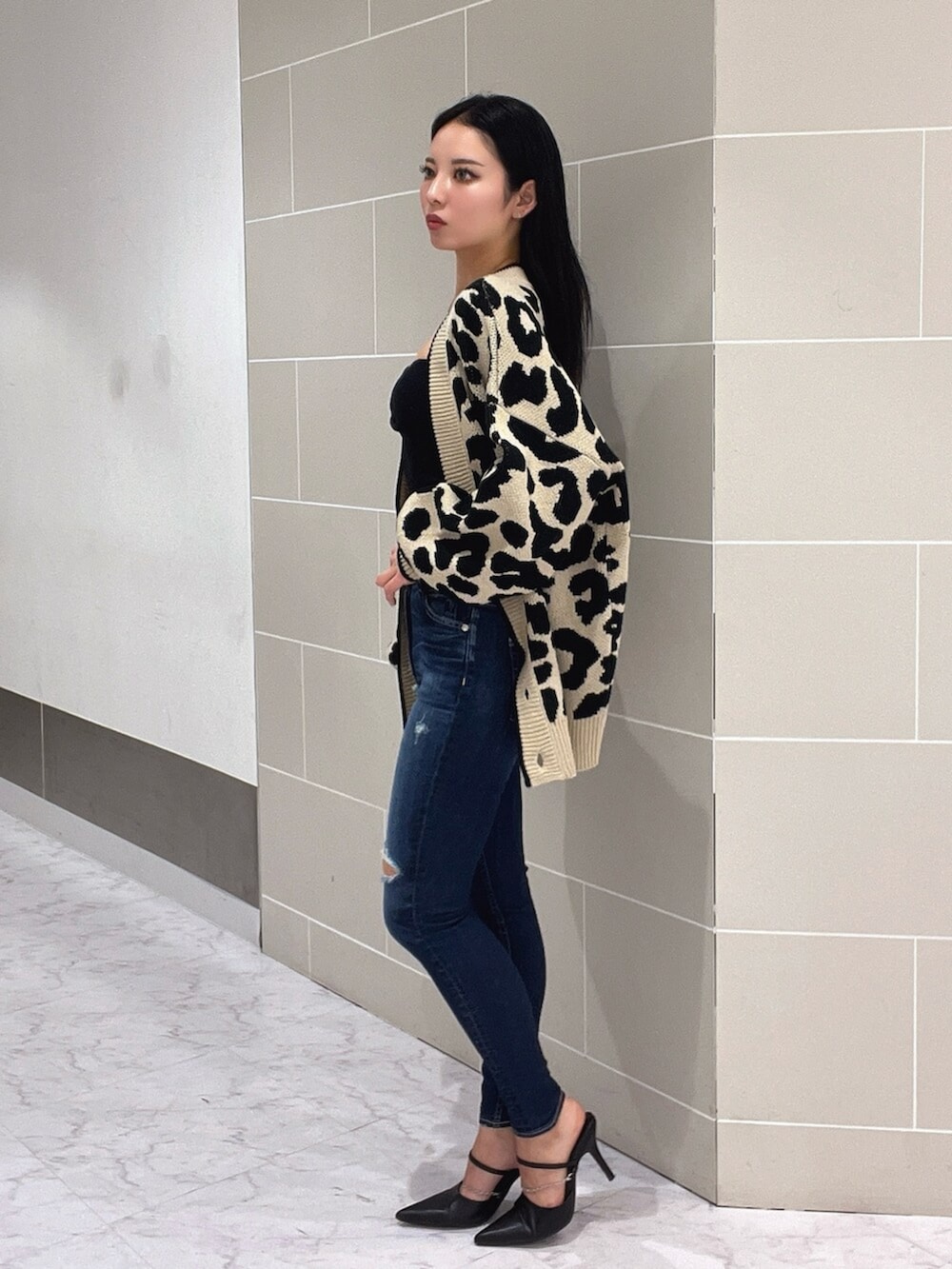 ブラック系のキャミソール、ブラック系のパンプス、ブルー系のデニムパンツを着用したレディースの春コーディネートの4枚目の写真