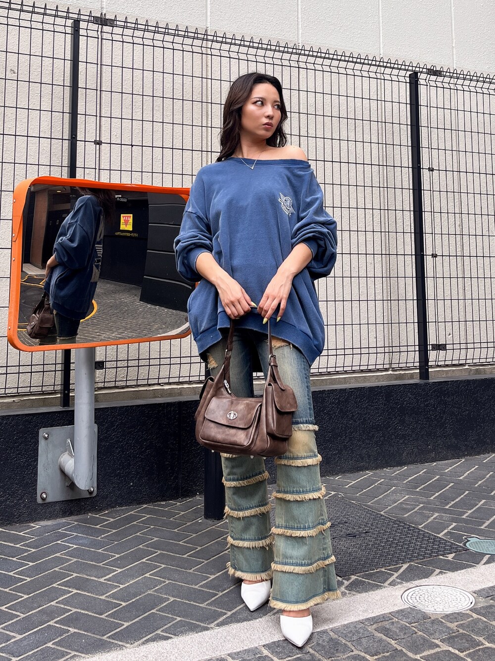 ブルー系のスウェット、ブルー系のデニムパンツ、ブラウン系のハンドバッグを着用したレディースの夏コーディネートの4枚目の写真