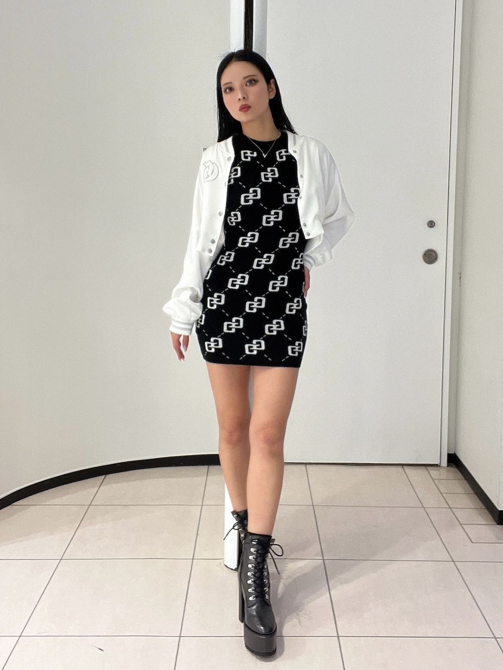 ブラック系のワンピース、ブラック系のブーツ、ホワイト系のブルゾンを着用したレディースの春コーディネートの2枚目の写真