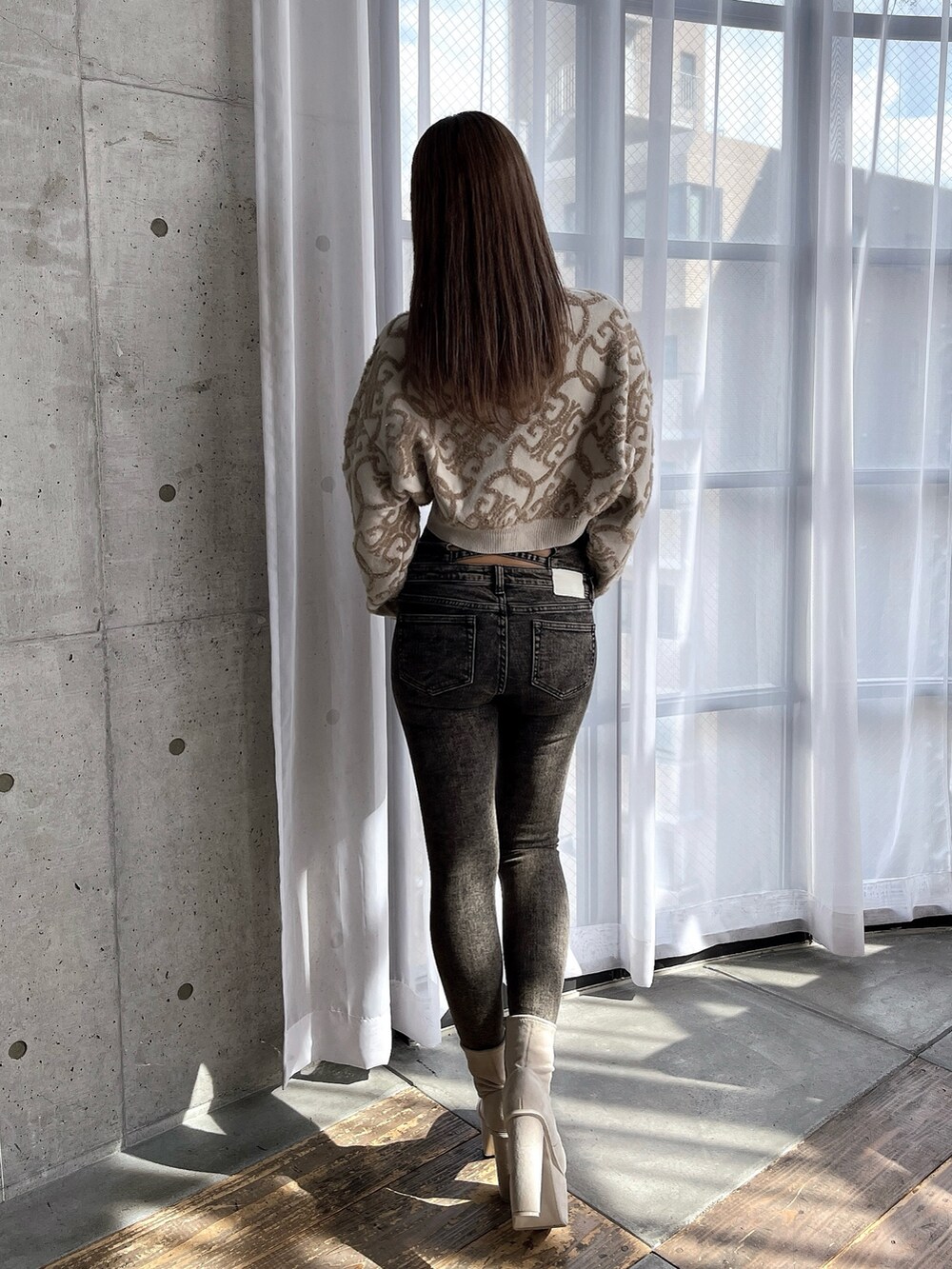 ホワイト系のニット/セーター、ブラック系のデニムパンツ、ホワイト系のブーツを着用したレディースの秋コーディネートの3枚目の写真