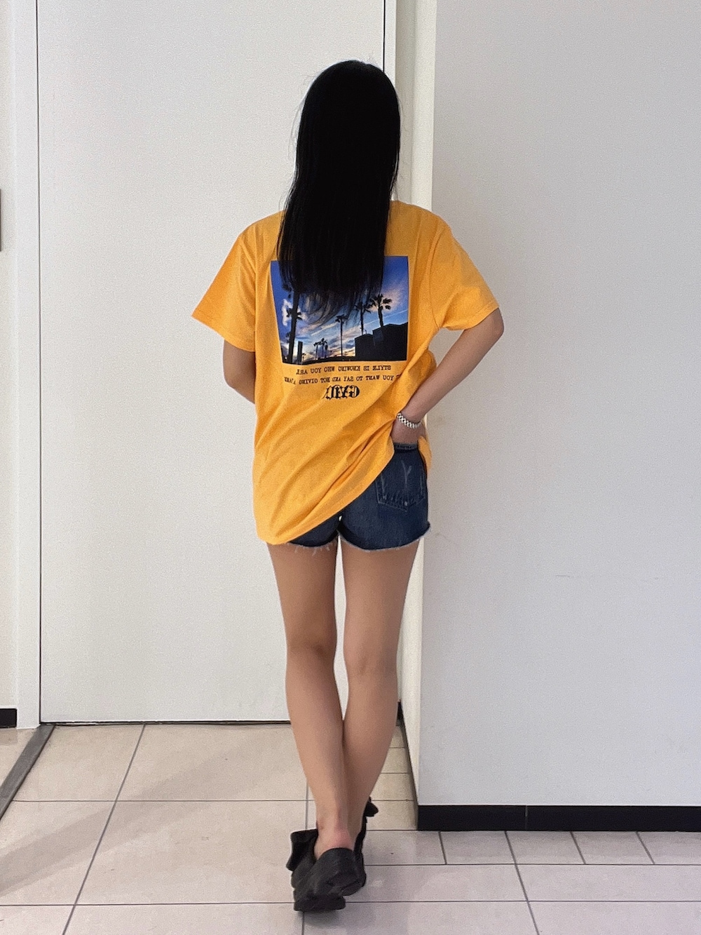 オレンジ系のTシャツ/カットソー、ブルー系のデニムパンツを着用したレディースの春コーディネートの5枚目の写真